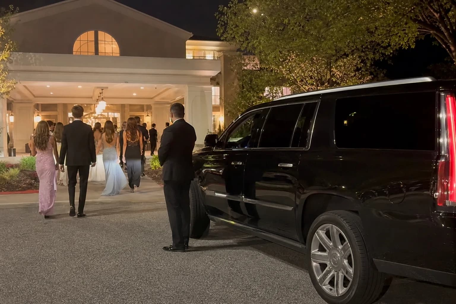 Black luxury SUV waiting outside an upscale evening event venue.